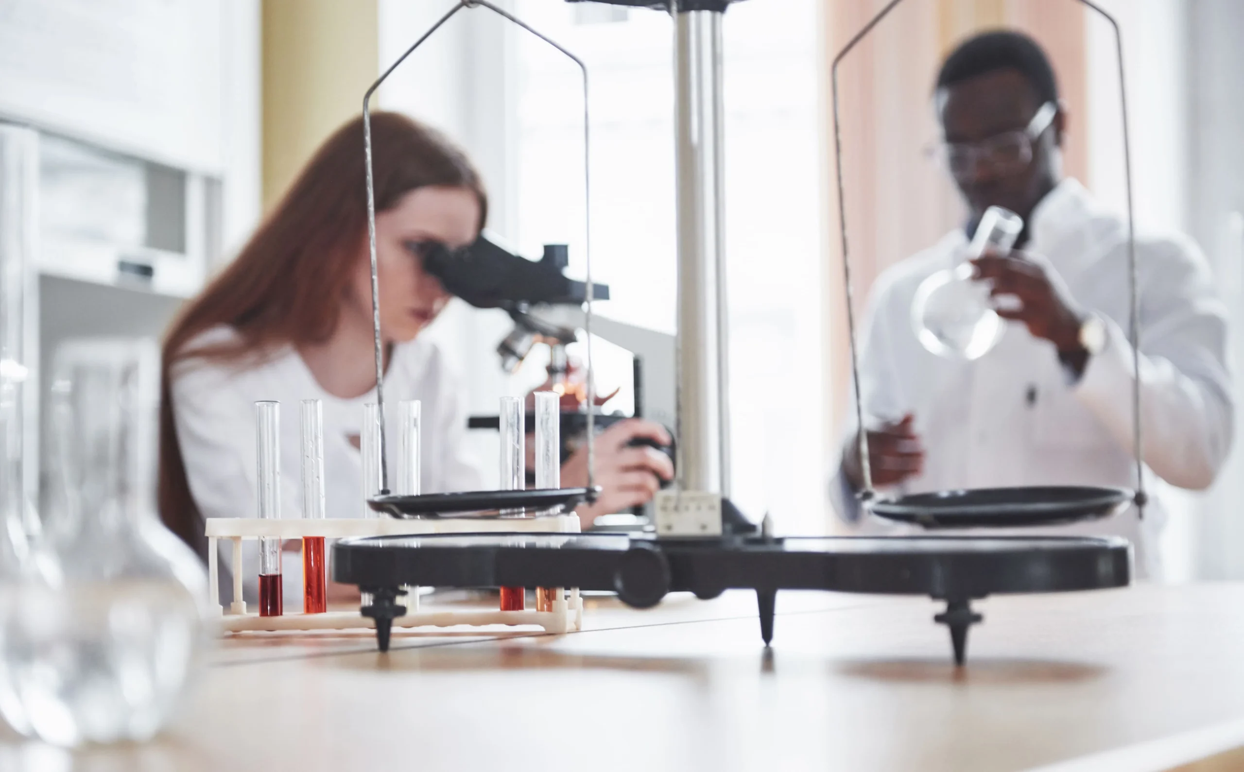 lab-assistant-with-microscope-laboratory-glassware-bulb-with-chemicals